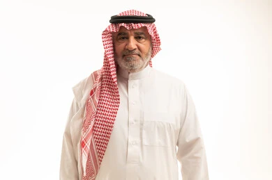Looking at the camera with gestures of seriousness and self-confidence, elegance and handsomeness, and attention to appearance, a close-up portrait of an elderly Saudi Arabian Gulf man wearing traditional attire standing upright, with a white background.