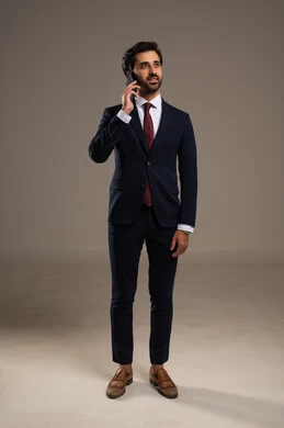 اجراء مكالمة هاتفية عبر الجوال، دمج التكنولوجيا في الحياة العملية، استخدام تقنية حديثة ومتطورة، إدارة شؤون العمل وتنظيمها عبر الإنترنت، بورتريه لرجل اعمال عربي خليجي سعودي يرتدي البدلة الرسمية يحمل بيده الهاتف المحمول, الجسم بالطول الكامل، خلفية بيضاء