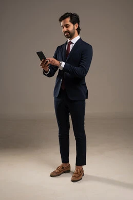 دمج التكنولوجيا في الحياة العملية، استخدام تقنية حديثة ومتطورة، إدارة شؤون العمل وتنظيمها عبر الإنترنت، بورتريه لرجل اعمال عربي خليجي سعودي يرتدي البدلة الرسمية يحمل بيده التابليت المحمول, الجسم بالطول الكامل، خلفية بيضاء