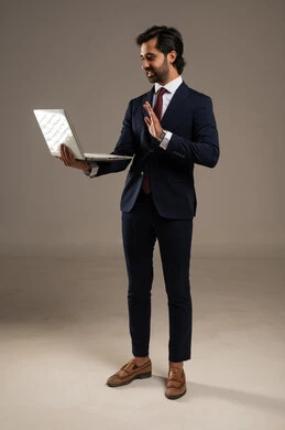 إدارة شؤون الأعمال وتنظيمها، استخدام التقنيات الحديثة المتطورة، عقد إجتماع عمل عبر الإنترنت، بورتريه لرجل اعمال عربي خليجي سعودي يرتدي البدلة الرسمية يقوم بالعمل على الحاسب المحمول, دمج التكنولوجيا في الحياة العملية، الجسم بالطول الكامل، خلفية بيضاء
