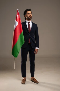 المشاركة بالاعياد والمناسبات الوطنية، الاحتفال بذكرى اليوم الوطني العماني، الاعتزاز والفخر بالرموز والراية العمانية، بورتريه لشاب عربي خليجي عماني يرتدي بدلة رسمية يحمل بيده علم سلطنة عمان، مفهوم حب الوطن والإنتماء إليه، الجسم بالطول الكامل، خلفية بيضاء