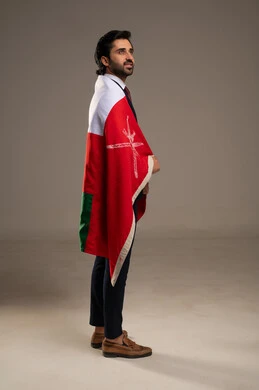 الاعتزاز والفخر بالرموز والراية العمانية، الاحتفال بذكرى اليوم الوطني العماني، مفهوم حب الوطن والإنتماء إليه، المشاركة بالاعياد والمناسبات الوطنية، بورتريه لشاب عربي خليجي عماني يرتدي بدلة رسمية يضع على كتفه علم سلطنة عمان، الجسم بالطول الكامل، خلفية بيضاء