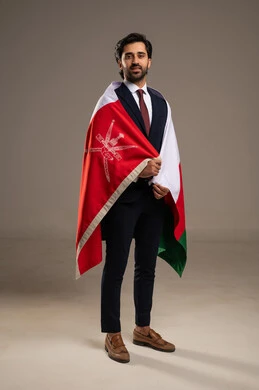 حب الوطن والإنتماء إليه، الفخر بالرموز والراية العمانية، الاحتفال بذكرى اليوم الوطني العماني، المشاركة بالاعياد والمناسبات الوطنية، بورتريه لشاب عربي خليجي عماني يرتدي بدلة رسمية يضع على كتفه علم سلطنة عمان، الجسم بالطول الكامل، خلفية بيضاء
