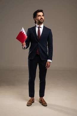 Celebrating Bahrain's National Day on December 16, a portrait of a Bahraini Gulf Arab man in a formal suit holding the flag of the Kingdom of Bahrain with gestures of pride and honor, national symbols and cultures, love for the homeland and belonging to it, commemorating the anniversary of the state's independence on August 14, full body length, white background.
