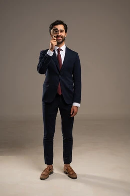 الفحص والاستكشاف والرؤية عن قرب، مفهوم توضيح الصورة، بورتريه لرجل عربي خليجي سعودي يرتدي الزي الرسمي ينظر من خلال العدسة المكبرة، التدقيق والتركيز باستخدام الأدوات البصرية، صورة لكامل الجسم، خلفية بيضاء