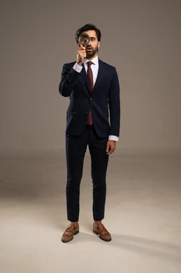 الفحص والاستكشاف والرؤية عن قرب، مفهوم توضيح الصورة، بورتريه لرجل عربي خليجي سعودي يرتدي الزي الرسمي ينظر من خلال العدسة المكبرة، التدقيق والتركيز باستخدام الأدوات البصرية، صورة لكامل الجسم، خلفية بيضاء