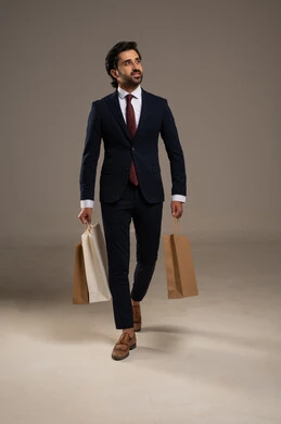Shopping and taking the necessary supplies, benefiting from discount and clearance seasons, commercial purchases and gifts, a portrait of a Saudi Arabian Gulf man wearing official attire and holding paper bags in his hand, full body image, white background.