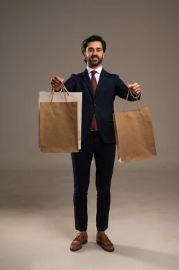 الاستفادة من مواسم الحسومات والتصفيات، التبضع وأخذ الاحتياجات اللازمة, المشتريات التجارية والهدايا, بورتريه لرجل عربي خليجي سعودي يرتدي الزي الرسمي و يمسك بيده أكياس ورقية، صورة الجسم بالكامل، خلفية بيضاء