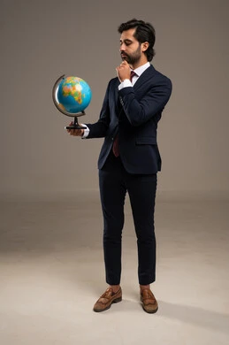The concept of research and exploration around the world, a portrait of a smiling Arab Gulf Saudi man wearing a formal suit holding a globe model in his hand, full-body image, white background.