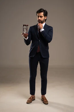 Thinking and daydreaming, the concept of business management and organizing the schedule, realizing the value of precious moments, monitoring the timing of sand, a portrait of a Saudi Arabian Gulf man wearing a formal suit holding a glass hourglass (bankam) in his hand, full-body, white background.