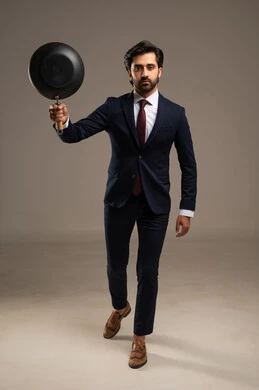 بتعابير وجه عدوانية ومتمردة وعدم السيطرة على النفس، الاهتمام بالمظهر الخارجي والرجولة، بورتريه لرجل أعمال عربي خليجي سعودي يرتدي البدلة الرسمية يقف يحمل بيده مقلا باللون الأسود مستعداً لتوجيه ضربة قوية، خلفية بيضاء