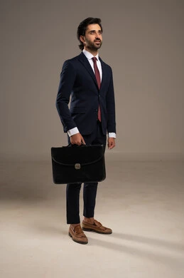 الذوق الرفيع والعملية اليومية، الوقوف بثقة وثبات، الاهتمام بالمظهر الخارجي والثقة بالنفس، بورتريه لرجل أعمال عربي خليجي سعودي يرتدي البدلة الرسمية يقف  ويحمل حقيبة أعمال جلدية,  خلفية بيضاء