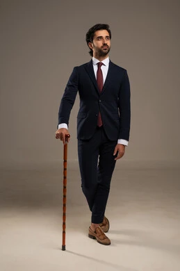 Decorated or engraved handle canes, attention to appearance and self-confidence, a portrait of a Saudi Gulf Arab businessman wearing a formal suit standing and holding a decorated cane, which adds to breaking the traditional pattern, white background.