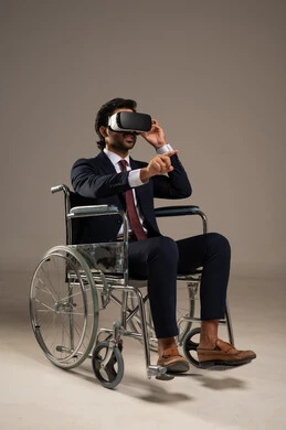 Enjoying watching virtual reality movies, integrating advanced technology into daily life, spending enjoyable and entertaining times with virtual games, a portrait of an Arab Gulf Saudi man wearing a formal suit sitting in a wheelchair and wearing 3D virtual reality glasses, white background.