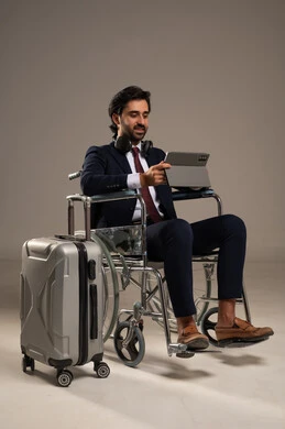 إجراء مكالمات الفيديو باستخدام جهاز التابلت، الاستفادة من التقنيات الحديثة والتكنولوجيا المتطورة، بورتريه لشاب عربي خليجي سعودي من ذوي الاحتياجات الخاصة يرتدي البدلة الرسمية يجلس على كرسي متحرك يتواصل مع الأهل والأصدقاء بإيماءات الاندماج، خلفية بيضاء
