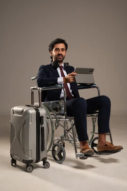 Utilizing modern technologies and advanced technology, making video calls using a tablet device, a portrait of a young Arab Gulf Saudi man with special needs wearing a formal suit sitting in a wheelchair communicating with family and friends before traveling with a suitcase beside him, white background. Utilizing modern technologies and advanced technology, making video calls using a tablet device, a portrait of a young Arab Gulf Saudi man with special needs wearing a formal suit sitting in a wheelchair communicating with family and friends before traveling with a suitcase beside him, white background.
