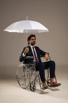 Protection from rain in winter, integrating people with disabilities into Saudi society, shading from sunlight, a portrait of a seated Arab Gulf Saudi man in formal attire sitting in a wheelchair holding an umbrella, full-body image, white background.