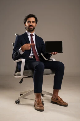 A black screen display, using modern technological devices, shopping online using a tablet, spending time browsing social media, completing tasks remotely, a close-up portrait of an Arab Saudi Gulf man wearing a formal suit sitting on a comfortable chair and using a tablet, white background.