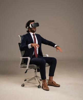 استخدام جهاز تقني حديث، الاندماج و التفاعل مع الواقع الافتراضي, محاكاة العالم الخيالي, محاولة النقر على شيء ما, بورتريه لرجل عربي خليجي سعودي يرتدي البدلة الرسمية يجلس على كرسي مريح يضع نظارات ثلاثية الأبعاد يقوم برفع اصبع السبابة للاعلى، خلفية بيضاء