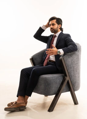 التفاعل والاندماج مع المباريات، رجل سعودي يقوم بتشجيع المنتخب الوطني,  بورتريه لشاب عربي خليجي سعودي يرتدي الطقم الرسمي ويجلس على اريكة مريحة بايماءات الخوف من تسجيل الاهداف,  مفهوم الجمال والاناقة والرجولة، خلفية بيضاء