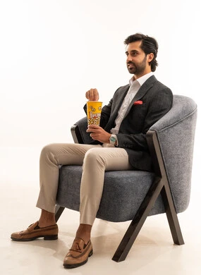 Spending free time watching entertaining movies and series, having a healthy and light snack, a portrait of a Saudi Arabian Gulf man wearing a formal suit sitting on a comfortable sofa and eating popcorn, white background. Spending free time watching entertaining movies and series, having a healthy and light snack, a portrait of a Saudi Arabian Gulf man wearing a formal suit sitting on a comfortable sofa and eating popcorn, white background.