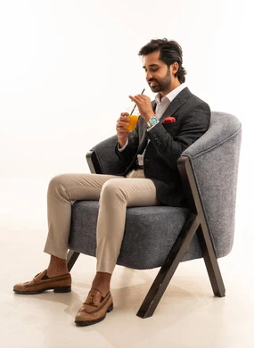 محاولة التخفيف من حرارة الصيف بالمشروب المنعش، الاستمتاع بالمشروبات المفيدة اللذيذة، بورتريه لرجل عربي خليجي سعودي مبتسم يرتدي البدلة الرسمية يجلس على كرسي مريح ويستمتع بشرب العصير الطبيعي البارد, خلفية بيضاء