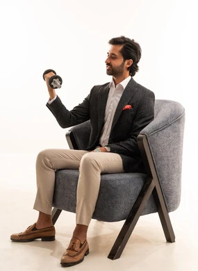 ممارسة التمارين الرياضية مع الدمبل, اهتمام بالرشاقة واللياقة، بورتريه لرجل أعمال عربي خليجي سعودي يرتدي البدلة الرسمية يجلس على كرسي مريح يرفع الأثقال (الدمبلز), الاهتمام بالمظهر الخارجي، خلفية بيضاء