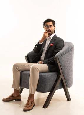 مضاعفة الأحجام ومحاولة إيجاد الأشياء الصغيرة، عمليات البحث والتدقيق، بورتريه لرجل عربي خليجي سعودي يرتدي البدلة الرسمية يجلس على كرسي يحاول اكتشاف شيء ما باستخدام العدسة المكبرة، إيماءات الاندماج والسرور، تكبير وتوضيح الرؤية، خلفية بيضاء