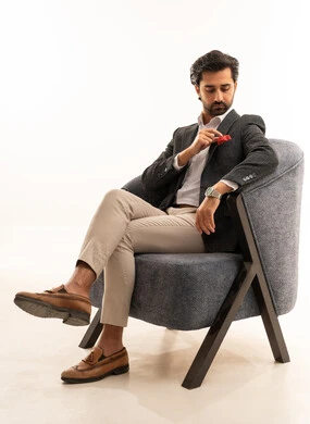 The concept of masculinity, elegance, and attention to appearance, a portrait of an Arab Gulf Saudi businessman wearing a formal suit sitting on a comfortable chair with gestures of self-confidence, white background.