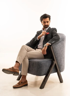 مفهوم الرجولة والأناقة والاهتمام بالمظهر الخارجي، بورتريه لرجل أعمال عربي خليجي سعودي يرتدي البدلة الرسمية يجلس على كرسي مريح بإيماءات الثقة بالنفس, خلفية بيضاء