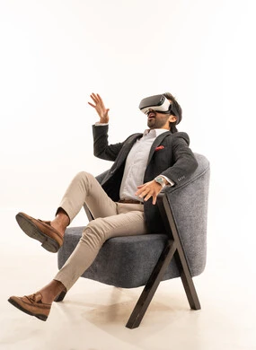 Interaction and simulation of the imaginary world, pointing to a place with expressions of integration and simulation of the imaginary world, attempting to click on something, a portrait of a Saudi Arabian Gulf man wearing a formal suit sitting on a comfortable chair wearing 3D glasses, white background.
