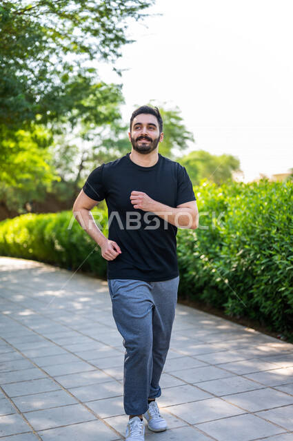 رجل عربي يمارس الرياضة الصباحية في الهواء الطلق ، ممارسة رياضة الجري ، ممارسة الرياضة على طريق الممشى المخصص للمشي بإحدى حدائق السعودية ، نشاط بدني للمحافظة على اللياقة والصحة الجيدة ، ممارسة التمارين الرياضية في وضع النهار