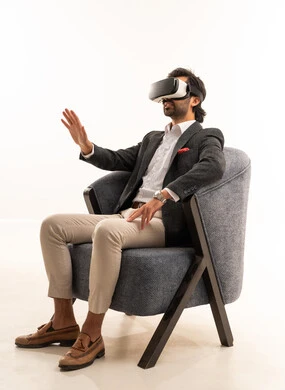 Interaction and simulation of the imaginary world, pointing to a place with expressions of integration and simulation of the imaginary world, attempting to click on something, a portrait of a Saudi Arabian Gulf man wearing a formal suit sitting on a comfortable chair wearing 3D glasses, white background.