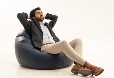 الحاجة إلى الاستراحة والنوم, الشعور بالتعب من ضغط العمل، بورتريه لرجل عربي خليجي سعودي يرتدي البدلة الرسمية يجلس على كرسي مريح يرفع يديه خلف رأسه بإيماءات الاسترخاء، خلفية بيضاء