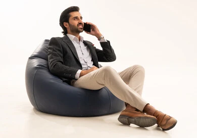 اجراء مكالمة هاتفية عبر الجوال، دمج التكنولوجيا في الحياة العملية، استخدام تقنية حديثة ومتطورة، إدارة شؤون العمل وتنظيمها عبر الإنترنت، بورتريه لرجل اعمال عربي خليجي سعودي يرتدي البدلة الرسمية يجلس على كرسي بين بادج مريح يحمل بيده الهاتف المحمول, خلفية بيضاء