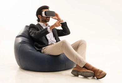 محاكاة العالم الخيالي, شاب سعودي يشير الى مكان ما بتعابير الاندماج ومحاكاة العالم الخيالي,  محاولة النقر على شيء ما, بورتريه لرجل عربي خليجي سعودي يرتدي البدلة الرسمية يجلس على كرسي مريح يضع نظارات ثلاثية الأبعاد يقوم برفع اصبع السبابة للاعلى، خلفية بيضاء