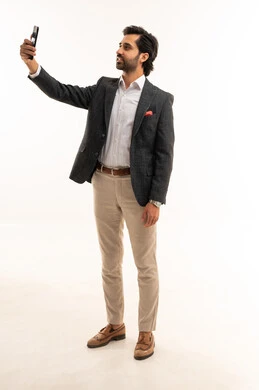 التقاط صورة سيلفي تذكارية عبر الجوال، دمج التكنولوجيا في الحياة العملية، استخدام تقنية حديثة ومتطورة، إدارة شؤون العمل وتنظيمها عبر الإنترنت، بورتريه لرجل اعمال عربي خليجي سعودي يرتدي البدلة الرسمية يحمل بيده الهاتف المحمول, الجسم بالطول الكامل، خلفية بيضاء