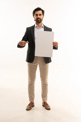 رفع اصبع السبابة والاشارة للوحة، حملات اعلانية وتسويق، موك اب مستطيل ابيض،  مفهوم الاناقة والرجولة والاهتمام بالمظهر الخارجي، بورتريه لشاب عربي خليجي سعودي يرتدي البدلة الرسمية يحمل لوحة مستطيلة بيضاء, الجسم بالطول الكامل، خلفية بيضاء