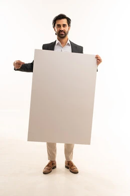 حملات اعلانية وتسويق، رفع اصبع السبابة والاشارة للوحة، موك اب مستطيل ابيض،  مفهوم الاناقة والرجولة والاهتمام بالمظهر الخارجي، بورتريه لشاب عربي خليجي سعودي يرتدي البدلة الرسمية يحمل لوحة كبيرة مستطيلة بيضاء, الجسم بالطول الكامل، خلفية بيضاء