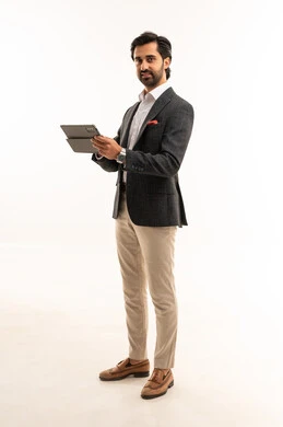 استخدام تقنية حديثة ومتطورة، إدارة شؤون الأعمال وتنظيمها، عقد إجتماع عمل عبر الإنترنت، بورتريه لرجل اعمال عربي خليجي سعودي يرتدي البدلة الرسمية يحمل بيده التابليت المحمول, دمج التكنولوجيا في الحياة العملية، الجسم بالطول الكامل، خلفية بيضاء