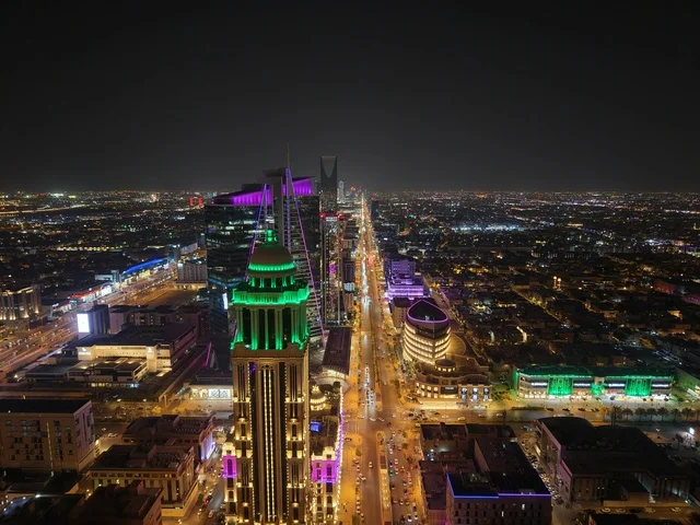 The architectural engineering art of buildings and commercial and residential establishments in a modern style, urban growth and development, car traffic in the brightly lit streets of the capital at night, the concept of infrastructure development in the city of Riyadh, towers and skyscrapers in the Kingdom of Saudi Arabia.