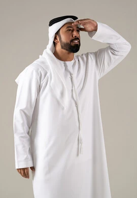 التخطيط للأهداف والطموحات المستقبلية، محاولة تقريب الأشياء البعيدة، التركيز على شيء ما، بورتريه لرجل عربي خليجي اماراتي يرتدي الكندورة والغترة يضع يده فوق عينه، خلفية رمادية