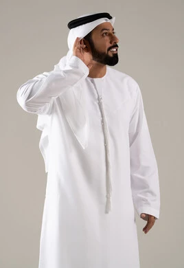 سماع الأحاديث و النقاشات، محاولة التجسس والتنصت, بورترية لرجل عربي خليجي اماراتي يرتدي الكندورة والغترة يضع يديه خلف اذنيه، إيماءات الإنصات وكشف الاسرار، خلفية رمادية