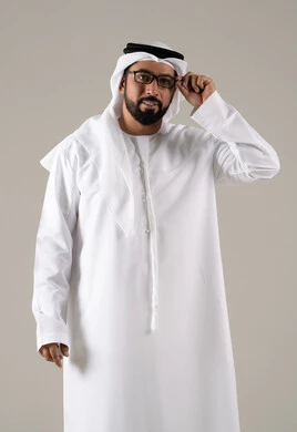 بورتريه لرجل عربي خليجي اماراتي يرتدي الكندورة والغترة والنظارات الطبيه ، الحاجه الى كشف النظر، مفهوم ضعف البصر، الاناقة والاهتمام بالمظهر الخارجي، خلفية رماديه