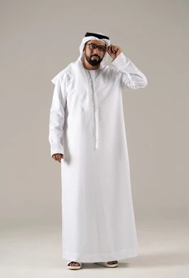 Elegance and attention to appearance, the need for vision correction, the concept of visual impairment, a portrait of an Arab Gulf Emirati man wearing a kandura, ghutrah, and prescription glasses, with a gray background.
