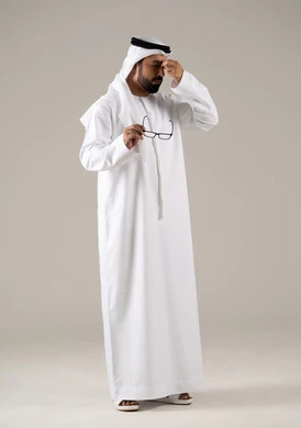 بورتريه لرجل عربي خليجي اماراتي يرتدي الكندورة والغترة والنظارات الطبيه ، ايماءات التعب والارهاق ، مفهوم ضعف البصر، الاناقة والاهتمام بالمظهر الخارجي،خلفية رماديه