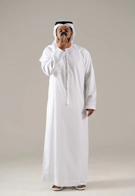 ايماءات الاستمتاع والاندماج، تناول المشروبات الساخنه ،مفهوم الاهتمام بالمظهر الخارجي، منتجات محلية وطنية سعودية، بورتريه لرجل عربي خليجي اماراتي يرتدي الكندورة والغترة يحمل بيدها كوب من القهوة، خلفية رمادية