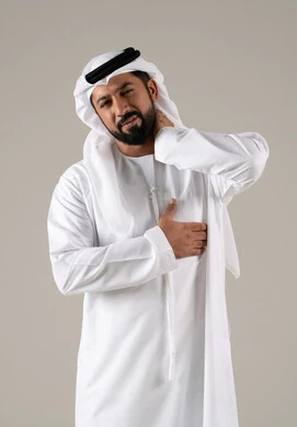 آلام الرقبة والعظام، إيماءات الاضطراب والتألم، ضرورة الذهاب للطبيب والحصول على العلاج، بورتريه لرجل عربي خليجي اماراتي يرتدي الكندورة والغترة يمسك رقبته بإيماءات الألم, خلفية رمادية