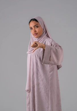 A portrait of a Saudi Arabian Gulf woman wearing an abaya and hijab, pointing her thumb down, gestures of disapproval, dislike, and rejection, discomfort with something, gray background.