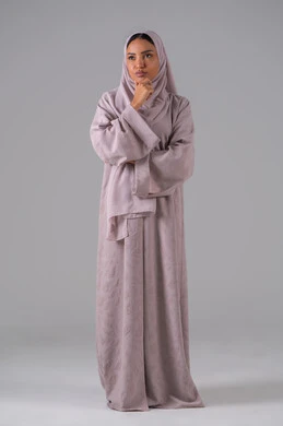 ايماءات التفكير والحيرة، مفهوم التأمل والتخطيط، تعابير التمعن والتركيز، بورتريه لإمرأة عربية خليجية سعودية  ترتدي العباءة والحجاب تضع يدها على ذقنها،خلفية رمادية